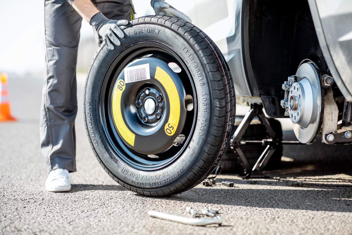 Close-up of a changing wheel process with jack, wrenches and spare wheel outdoors