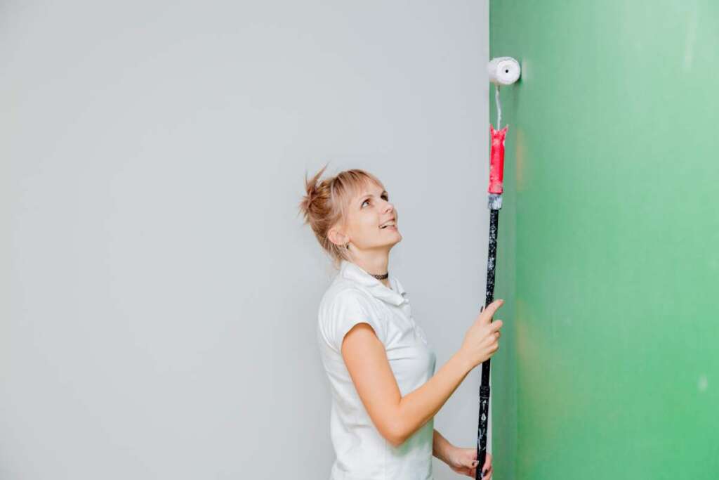 Young woman with paint roller in own house after painting a room. Real people